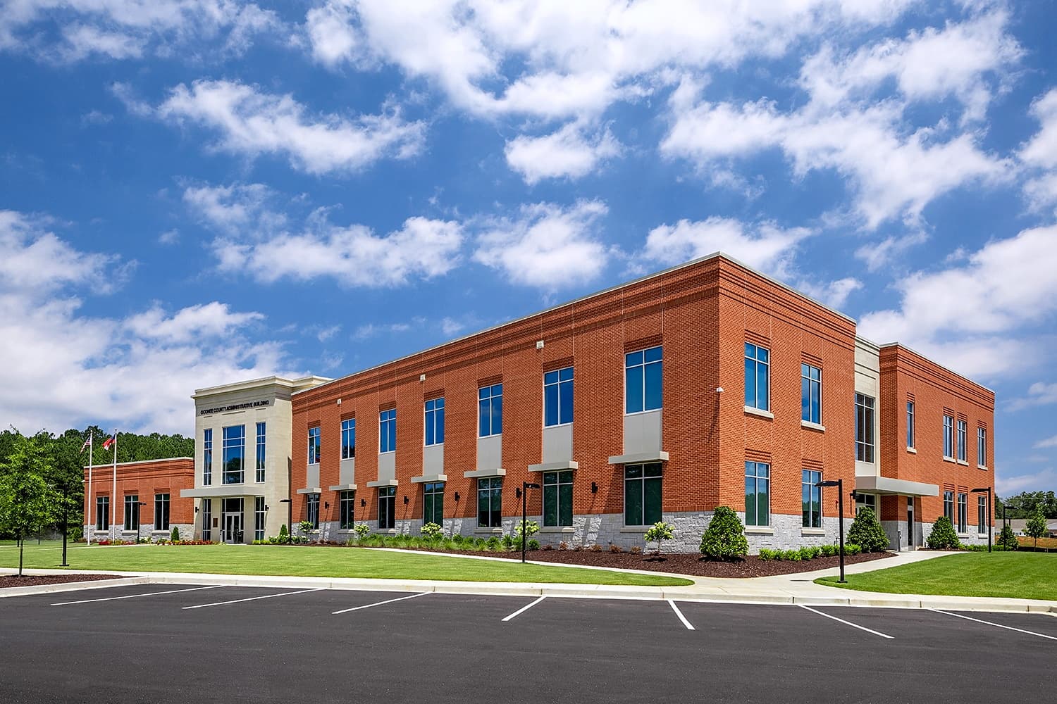 The Oconee County Administrative Building at 7635 Macon Highway in Watkinsville, Georgia — two-storey red brick with a cast-stone entry and flagpoles