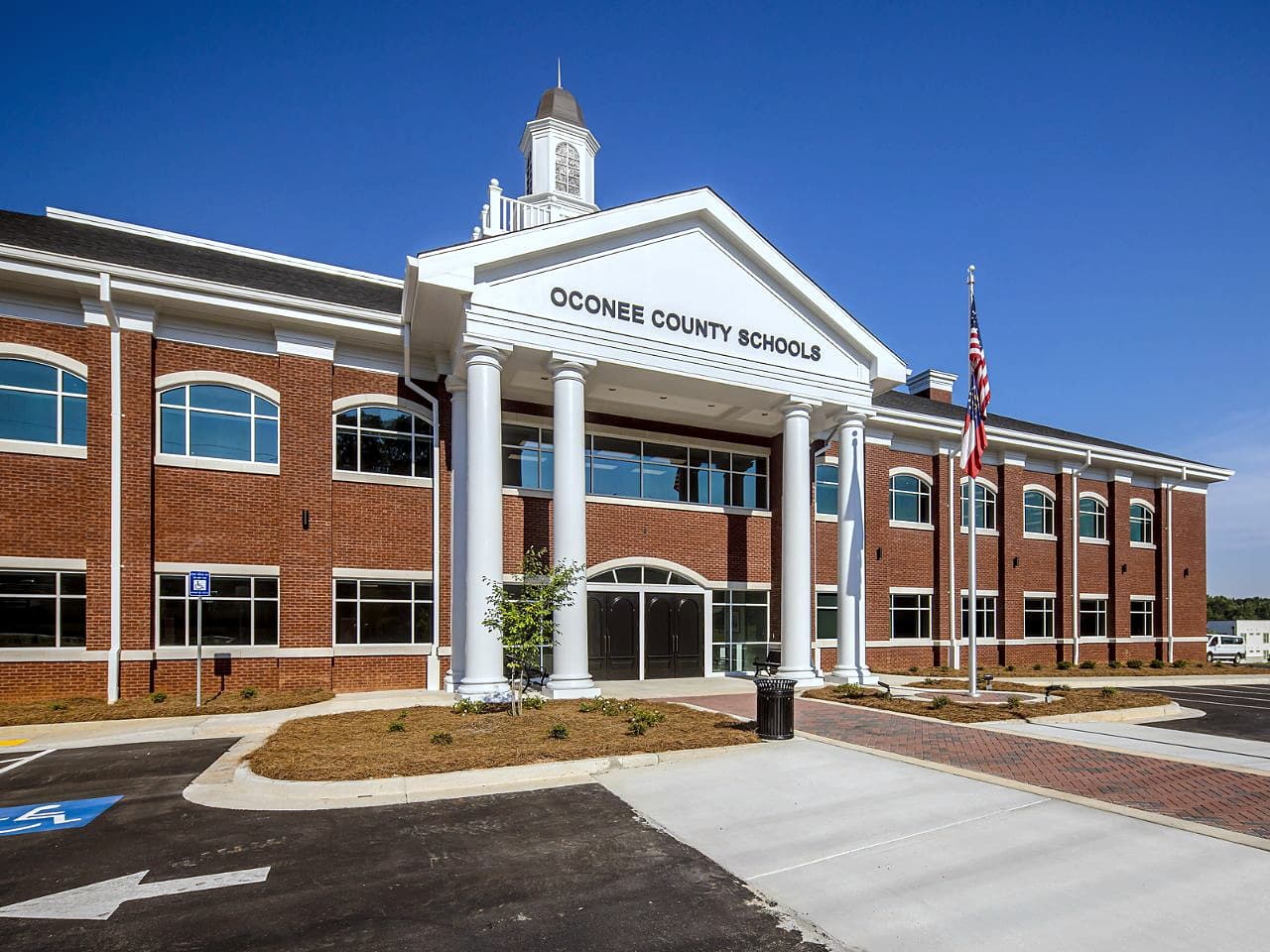 The front entrance of the Oconee County Schools district building — red brick with white columns, a pediment and a cupola